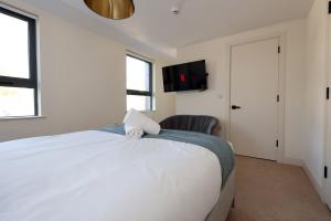 a bedroom with a white bed and a tv on the wall at Albert Hall 1 Bed ApartHotel- Food & Bar Onsite in Swansea
