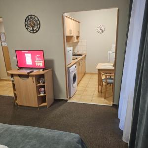 a room with a kitchen and a desk with a laptop at Karos Kristály Apartman in Zalakaros
