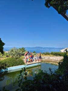 a group of people standing on a bridge over a pond at Villa Suzi - Family Farm Stay with Donkeys, Pool and Sea View near Rijeka in Šmrika