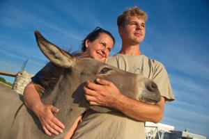 a man and a woman hugging a donkey at Villa Suzi - Family Farm Stay with Donkeys, Pool and Sea View near Rijeka in Šmrika