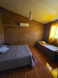 a bedroom with two beds and a brick wall at Complejo de departamentos 7 Cielos in Villa Carlos Paz