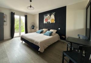 a bedroom with a large bed and a table at L Ecrin d Anabelle in Saint-Georges-lès-Baillargeaux
