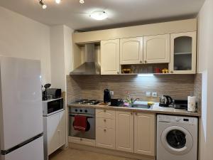 a kitchen with white cabinets and a sink and a refrigerator at Borealis Apartment in Bansko