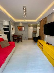 a living room with a red couch and a flat screen tv at Garden Moinhos de Vento in Porto Alegre