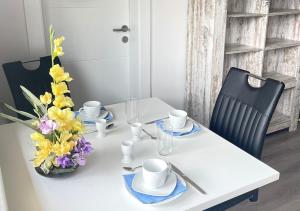 a white table with a vase of flowers on it at Apartment mit Balkon & Bergblick inklusive Parkplatz in Christofberg