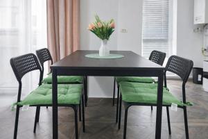 a black table with green chairs and a vase with flowers at Hera Exclusive Stay 2 in Timişoara