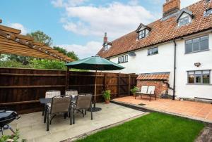 a patio with an umbrella and a table and chairs at 2 Bed in Saxtead oc-pera in Saxtead