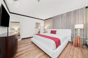 a white bedroom with a large bed and a flat screen tv at Metropole Suites South Beach in Miami Beach