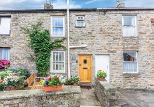 a brick house with a wooden door and potted plants at 2 Bed in Hawes oc-ds042a in Hawes