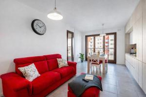 a living room with a red couch and a clock on the wall at Sarca 11th Floor in Milan