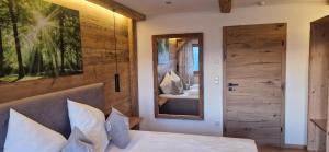 a bedroom with a bed and a mirror and a door at Chalet Auszeit - Wohlfühlzeit Naturdesign Chalet`s in Rimbach