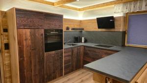 a kitchen with wooden cabinets and a counter top at Chalet Auszeit - Wohlfühlzeit Naturdesign Chalet`s in Rimbach