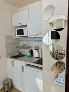 a white kitchen with white cabinets and a microwave at Panorama Studio Home2Host in Bansko