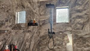 a shower in a bathroom with a stone wall at Jacaranda Escape in Pretoria