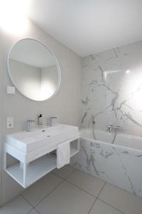 a white bathroom with a sink and a mirror at Maris Apartments in Egmond aan Zee +83 photos