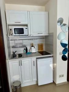 a kitchen with white cabinets and a sink and a microwave at Panorama Studio Home2Host in Bansko +7 photos