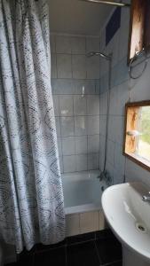a bathroom with a tub and a sink and a shower curtain at Cabaña con tinaja Aucaco in Ancud