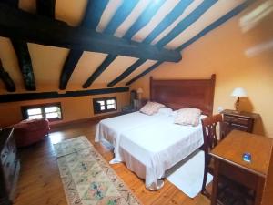 a bedroom with a white bed and a wooden floor at Casona de Gómez y Terán in Renedo