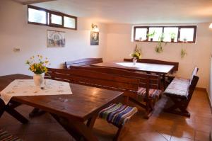 a living room with wooden tables and benches and windows at Onodilak Guesthouse - Vendégház in Bîrzava