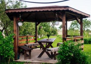 a wooden pavilion with a picnic table and benches at Onodilak Guesthouse - Vendégház in Bîrzava