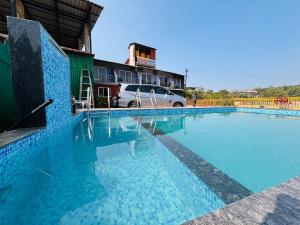 a swimming pool with a car parked next to a building at Aroma Residency 2bhk villa & delux rooms in Mahabaleshwar