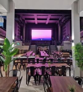 a restaurant with tables and chairs and a large screen at The Central Swansea Hall 1BR Apartment in Swansea