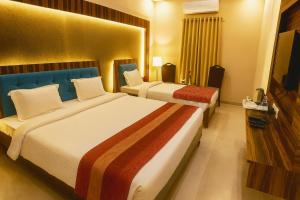 a hotel room with two beds and a flat screen tv at Hotel Crown Patliputra in Patna +1 photo