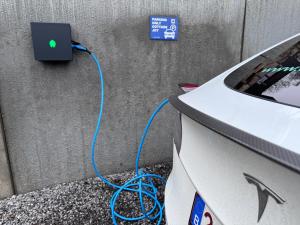 an electric car with a blue cord plugged into a wall at Meuse Cottage in Hastière-par-delà