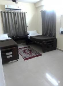 a room with two beds and a chair and a window at Zest Homes Nugambakkam in Chennai
