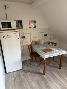a kitchen with a table and a white refrigerator at Pension Hoffmann Remscheid in Remscheid