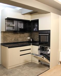 a kitchen with white cabinets and black appliances at Viva Nova Suit Hotel in Bakanlıklar