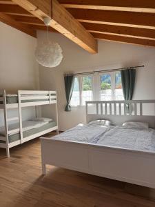 a bedroom with two white bunk beds and a wooden ceiling at Chalet Gadmer Herz in Gadmen
