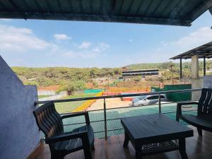 a balcony with a table and chairs and a view at Aroma Residency 2bhk villa & delux rooms in Mahabaleshwar