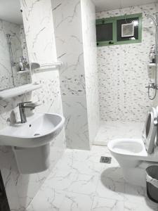a white bathroom with a sink and a toilet at Everest Stay in Abu Dhabi