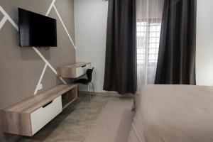 a bedroom with a bed and a tv on a wall at Zango Apartments in Shikalenge