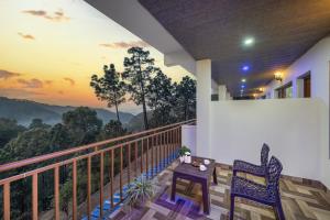 a balcony with two chairs and a table with a view at The Hills Station Nest - 4 Bedroom Villa by Splendid Retreat Hotels in Kasauli