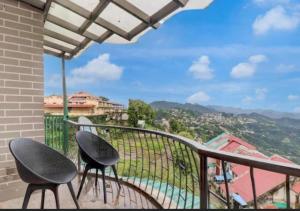 two chairs sitting on a balcony with a view at Fun Flock Stay in Mussoorie