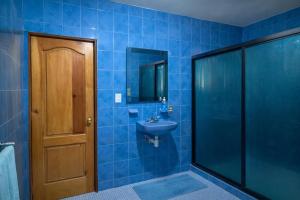 a blue tiled bathroom with a sink and a door at Hospedaje Rayo De Sol in Tepoztlán
