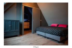ein Schlafzimmer mit einem Bett und einer Kommode mit rosa Kissen in der Unterkunft Cachoire in Tournai