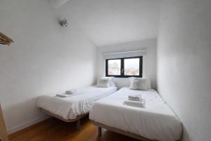 two beds in a room with white walls and a window at Oporto City View - Trindade in Porto
