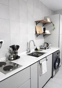 a white kitchen with a sink and a dishwasher at Riwaq suite in Jeddah +7 photos
