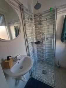 ein Badezimmer mit Waschbecken und Dusche mit Glastür in der Unterkunft casa cinna in Montà
