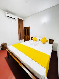 a bedroom with a large bed with yellow pillows at Villa Nevya in Weligama