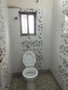 ein Badezimmer mit Toilette und Fenster in der Unterkunft Shriji in mayapur