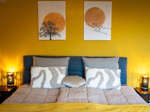a bed with two pillows and three paintings on the wall at Landhaus Kummerfrei in Hellenthal