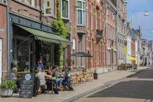 a group of people sitting at tables on a city street at Havenhuis Tilburg in Tilburg