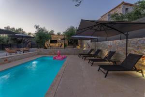 a swimming pool with chairs and an umbrella at Villa Omega in Lévktron