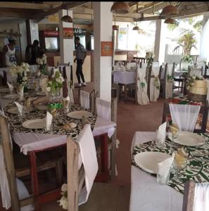 a dining room with tables with white plates and flowers at Dizzy Lizzies Beach House Resort in Kokrobite