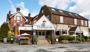 a building with tables and chairs in front of it at Raven Hotel by Greene King Inns in Hook