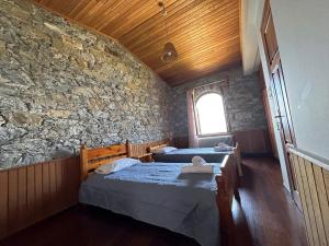 two beds in a room with a stone wall at Kofinas villa Evdilos by BRP-PROPERTIES in Evdilos